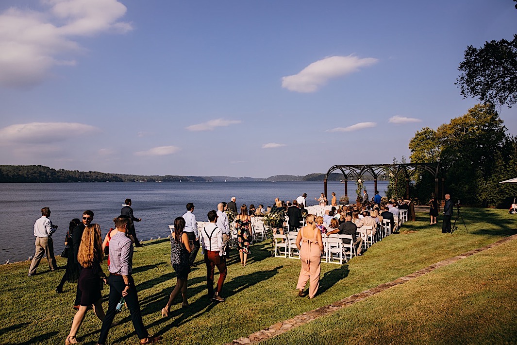 Wedding guests file to their seats on the edge of a lake.