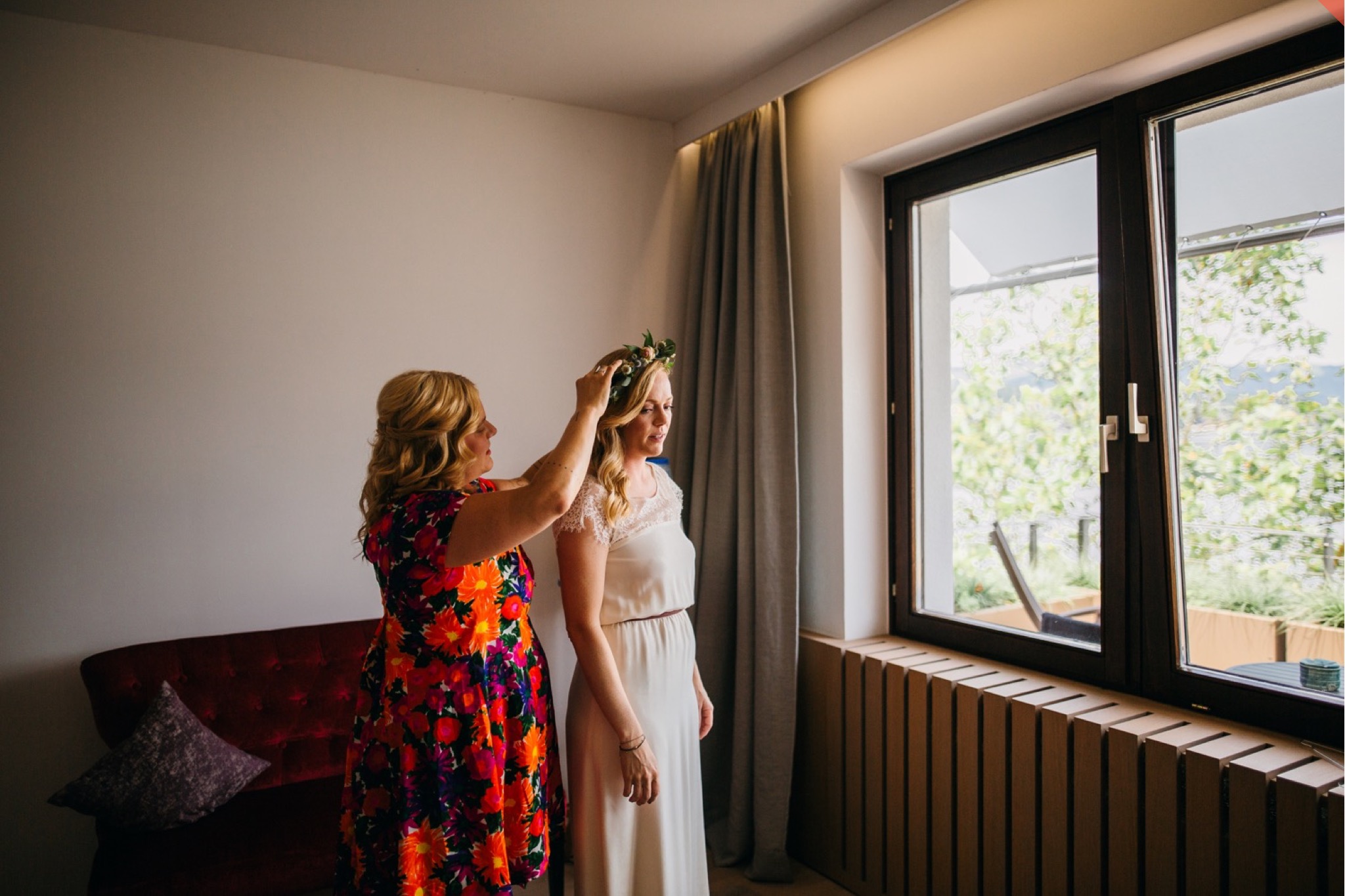 The bride gets help with her flower crown as she gets ready in her hotel room.