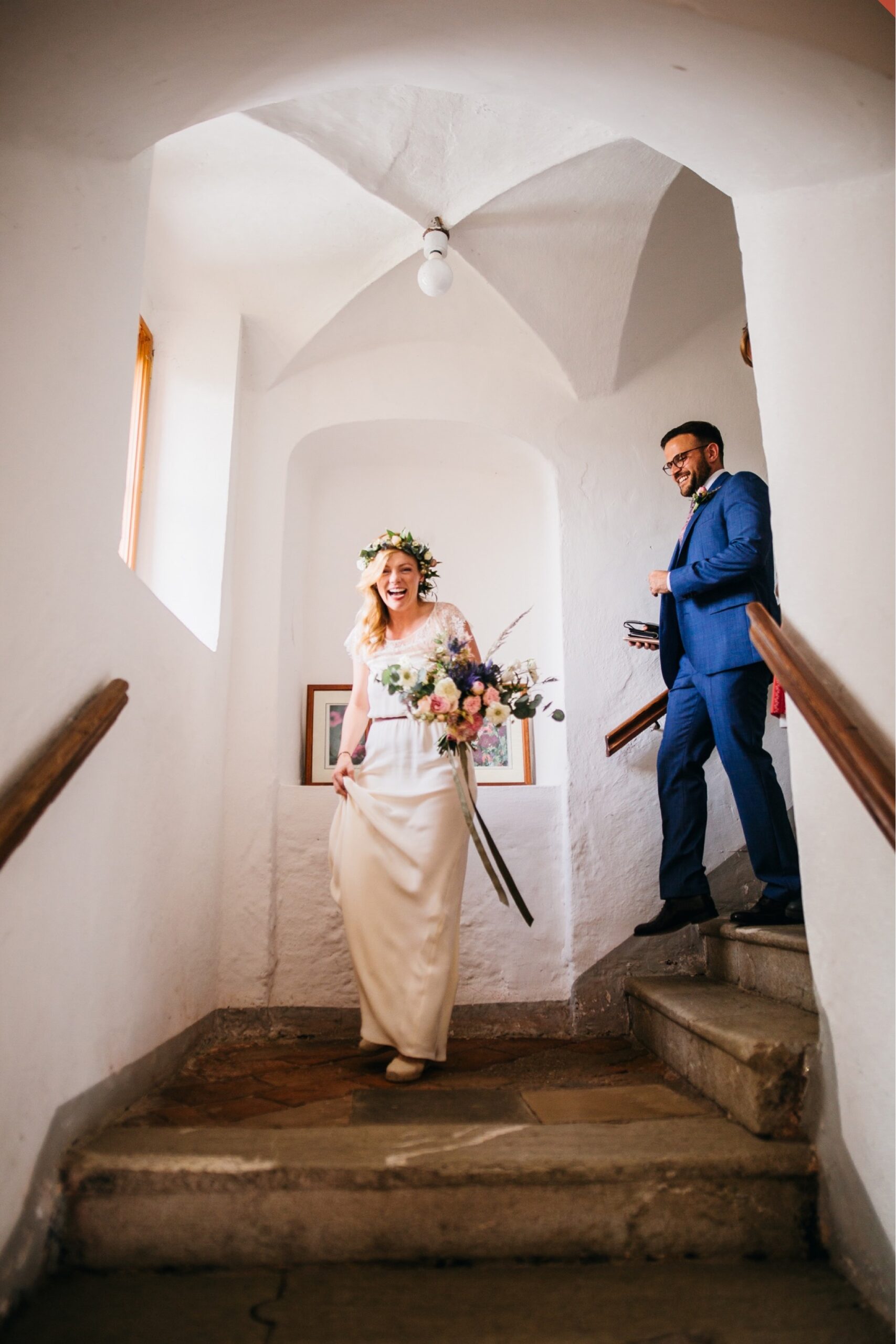 The bride and groom walk down a stone staircase in an Austrian courthouse.