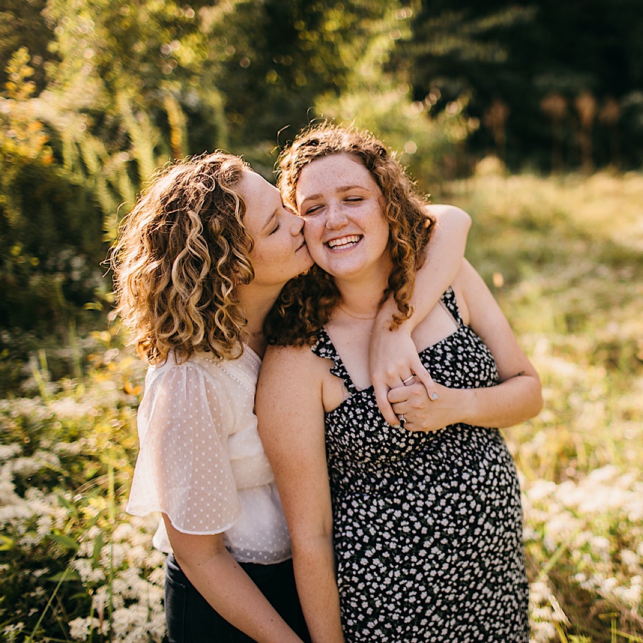 An engaged lesbian couple poses together in a field of Tennessee wildflowers.