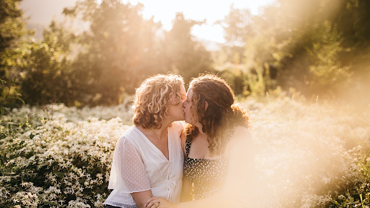 An engaged lesbian couple poses together in a field of Tennessee wildflowers.