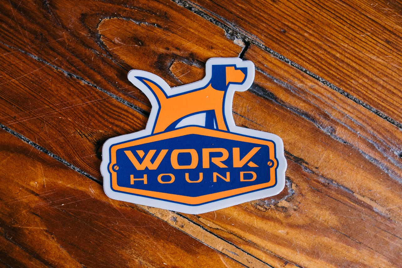 A stick of the Work Hound logo on a wooden background.