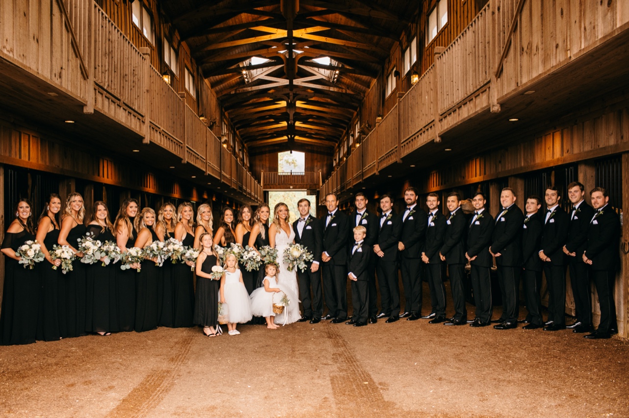Bride and groom pose with their bridal party in a barn.