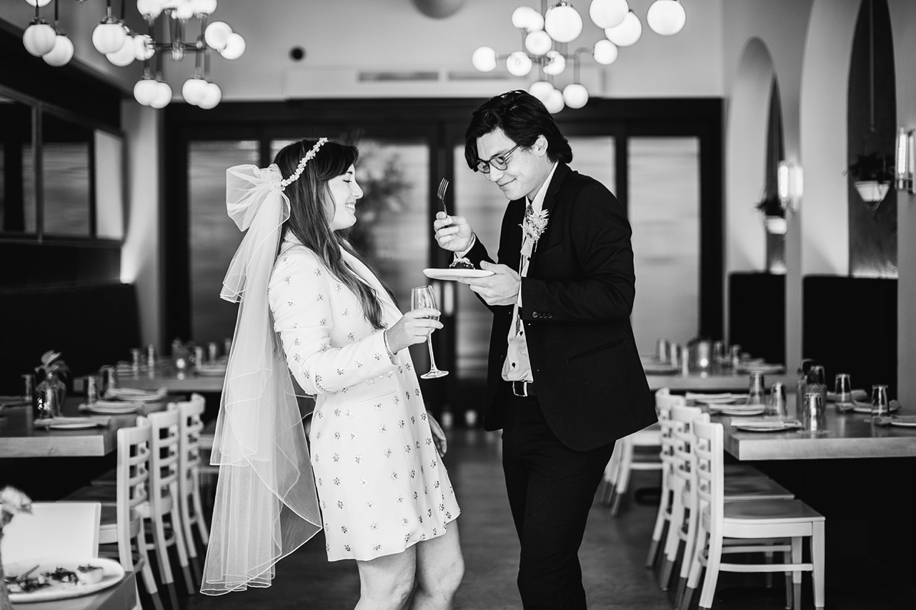 Bride and groom share cake and wine during their microwedding