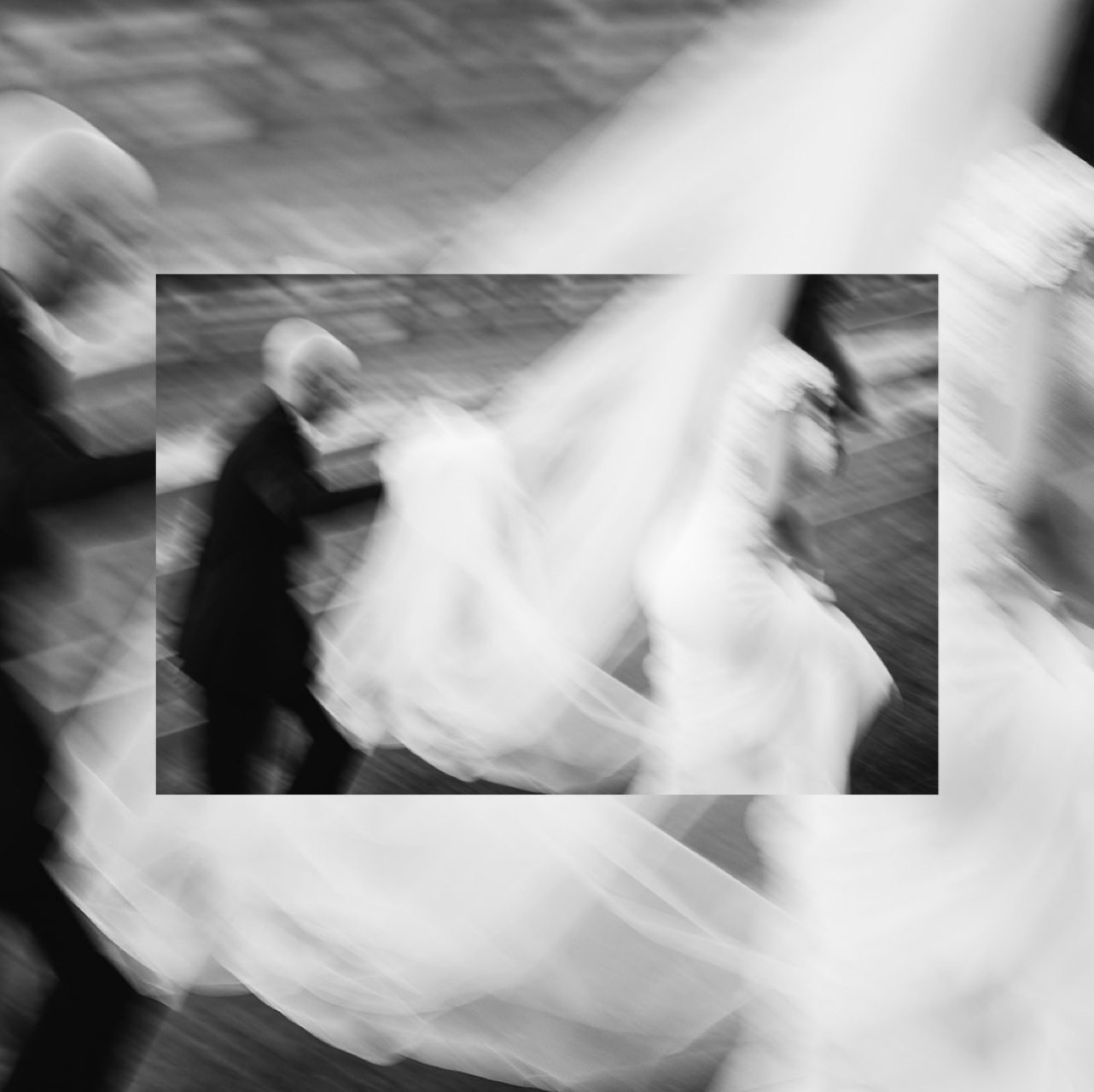A blurry image of the groom holding the bride's veil as she walks.
