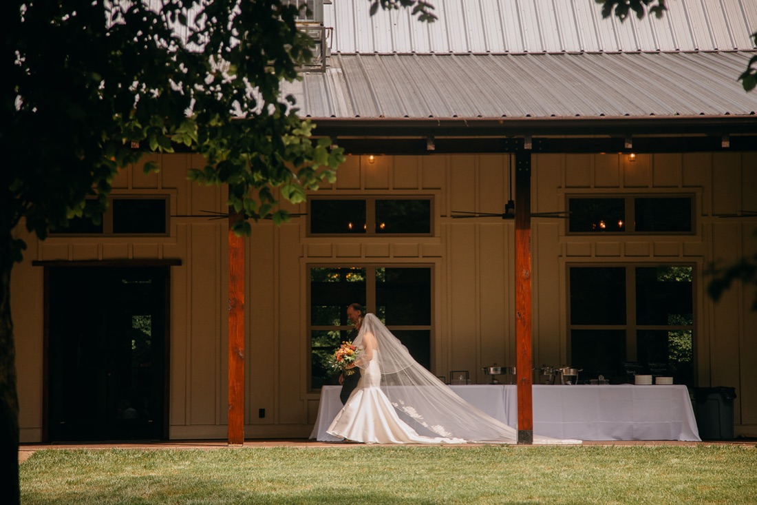 Hiwassee River Weddings & Events Photographer showcases the bride exiting the reception hall through two huge wooden doors, escorted by her father