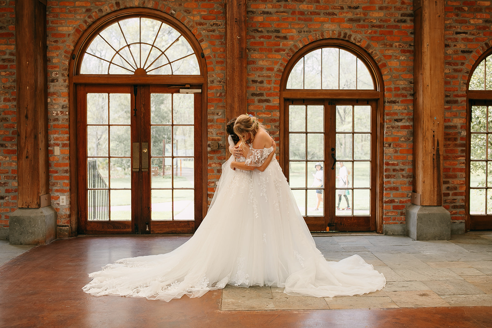 Bride and bride embrace after first look at their LSU Botanical Gardens wedding
