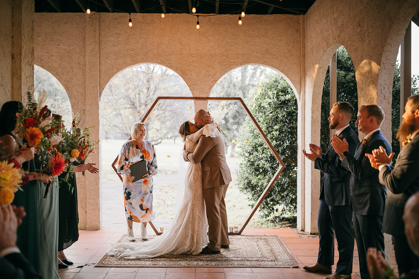 Bride and groom share first married kiss under arbor in natural light at wedding venues Chattanooga, TN outdoor. 
