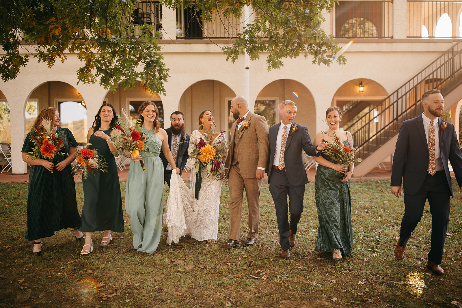 Wedding party walking together in front of the Spanish-style mansion at Tennessee River Place wedding venue. 