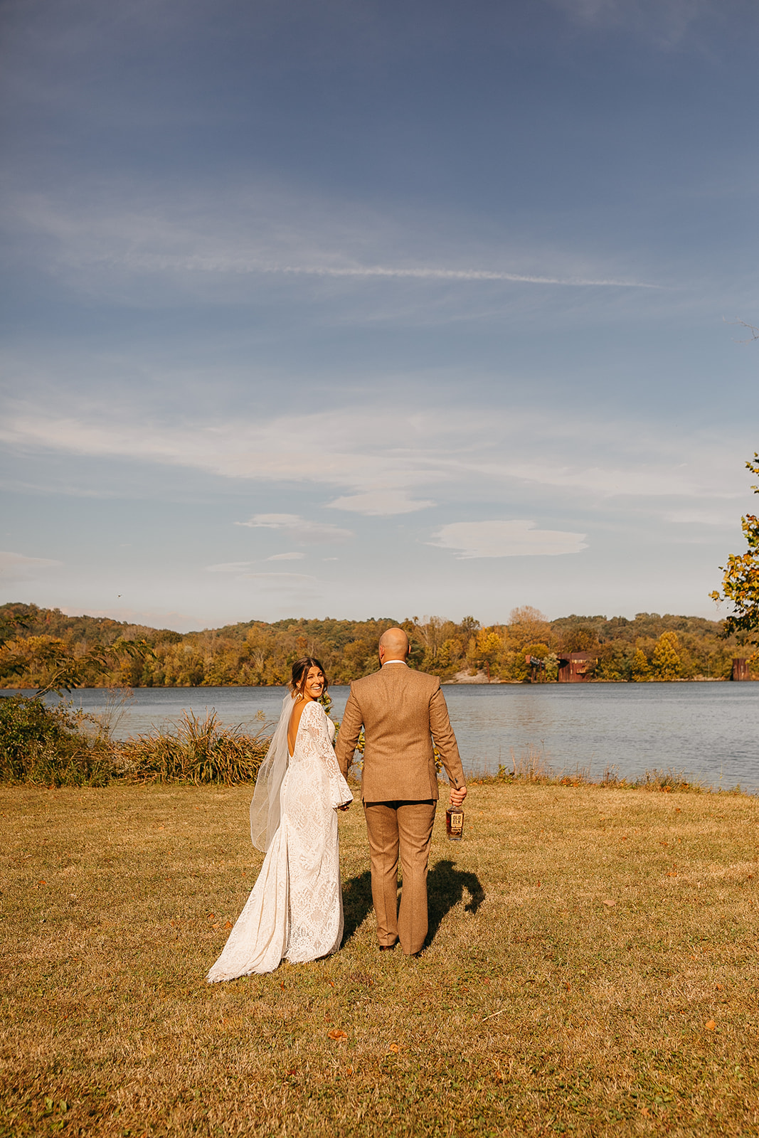 Bride and groom walking along the river with scenic views at Tennessee River Place wedding venue. 