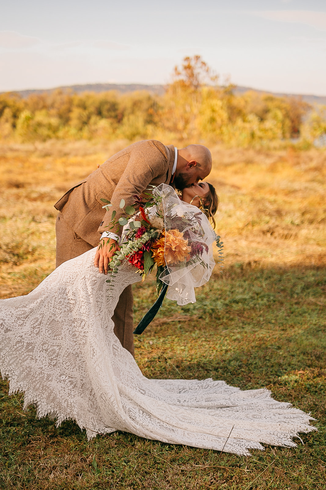 Romantic dip kiss with bouquet during golden hour at Tennessee River Place wedding venue. 
