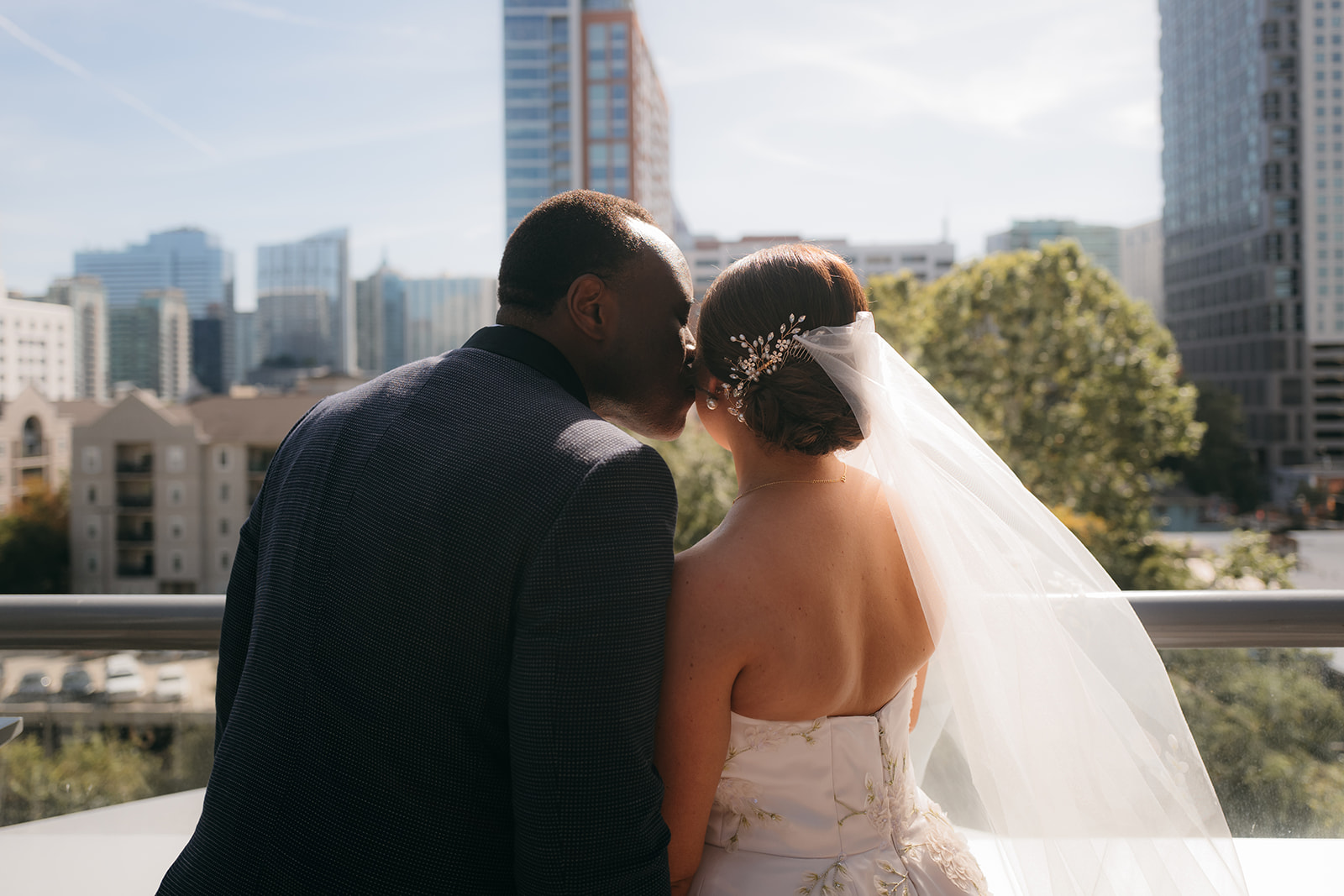 Bride and groom sharing a kiss overlooking the Atlanta skyline before their Atlanta Biltmore Ballrooms wedding ceremony. 