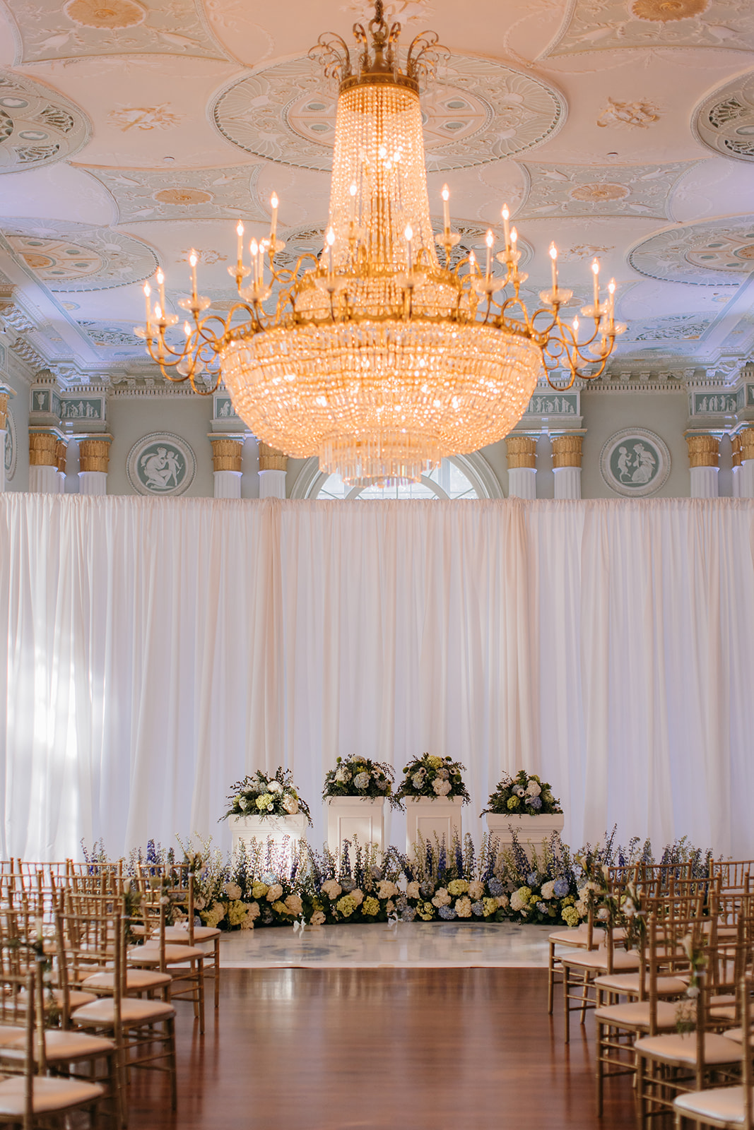 Ceremony setup inside the historic Biltmore Ballroom in Atlanta GA with floral aisle arrangements and crystal chandeliers 
