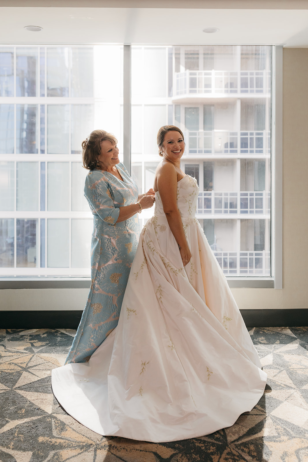 Mother helping the bride into her dress before the Atlanta Biltmore Ballrooms wedding ceremony. 