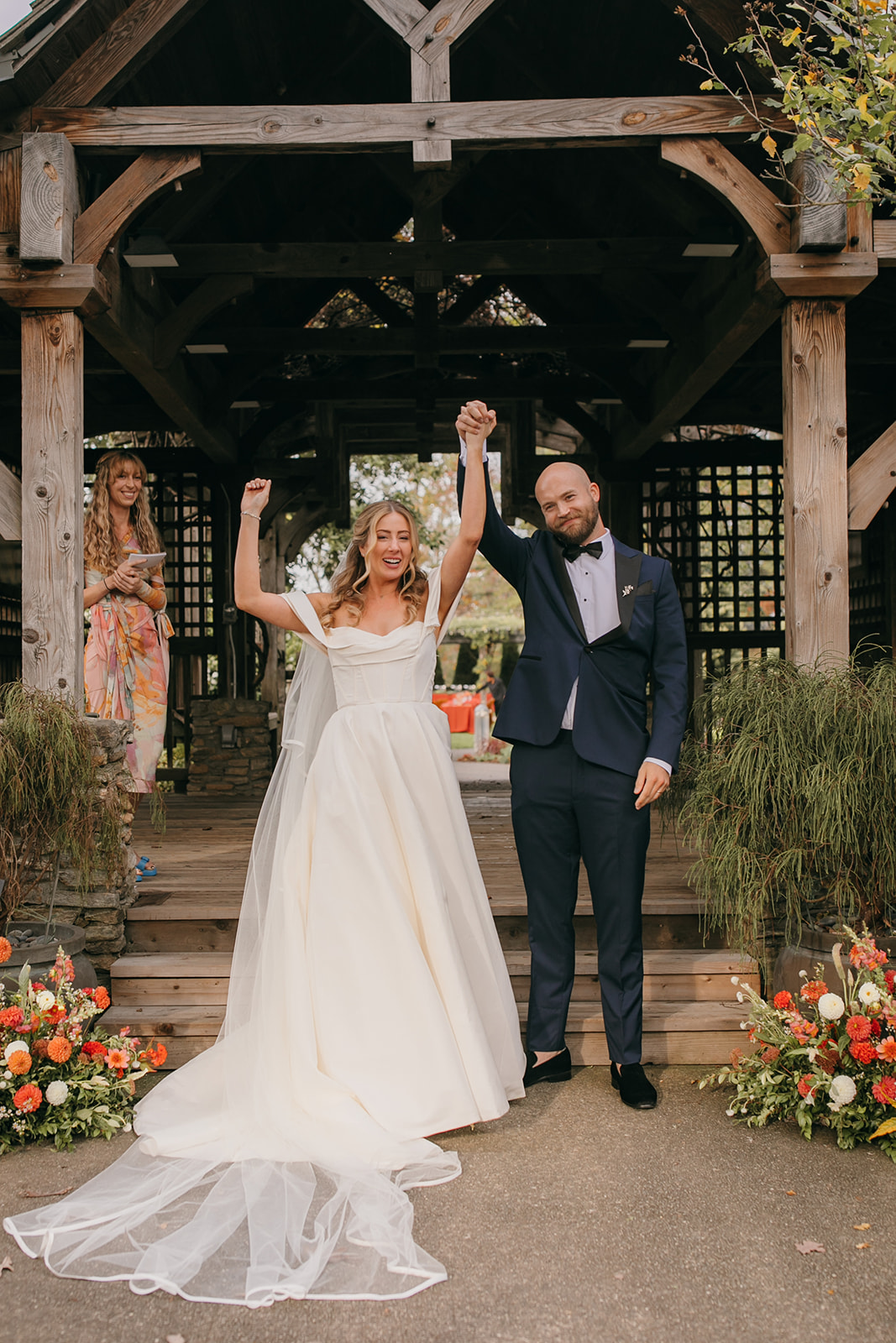 Bride and groom celebrating their ceremony exit at an NC Arboretum wedding beneath the garden pavilion.