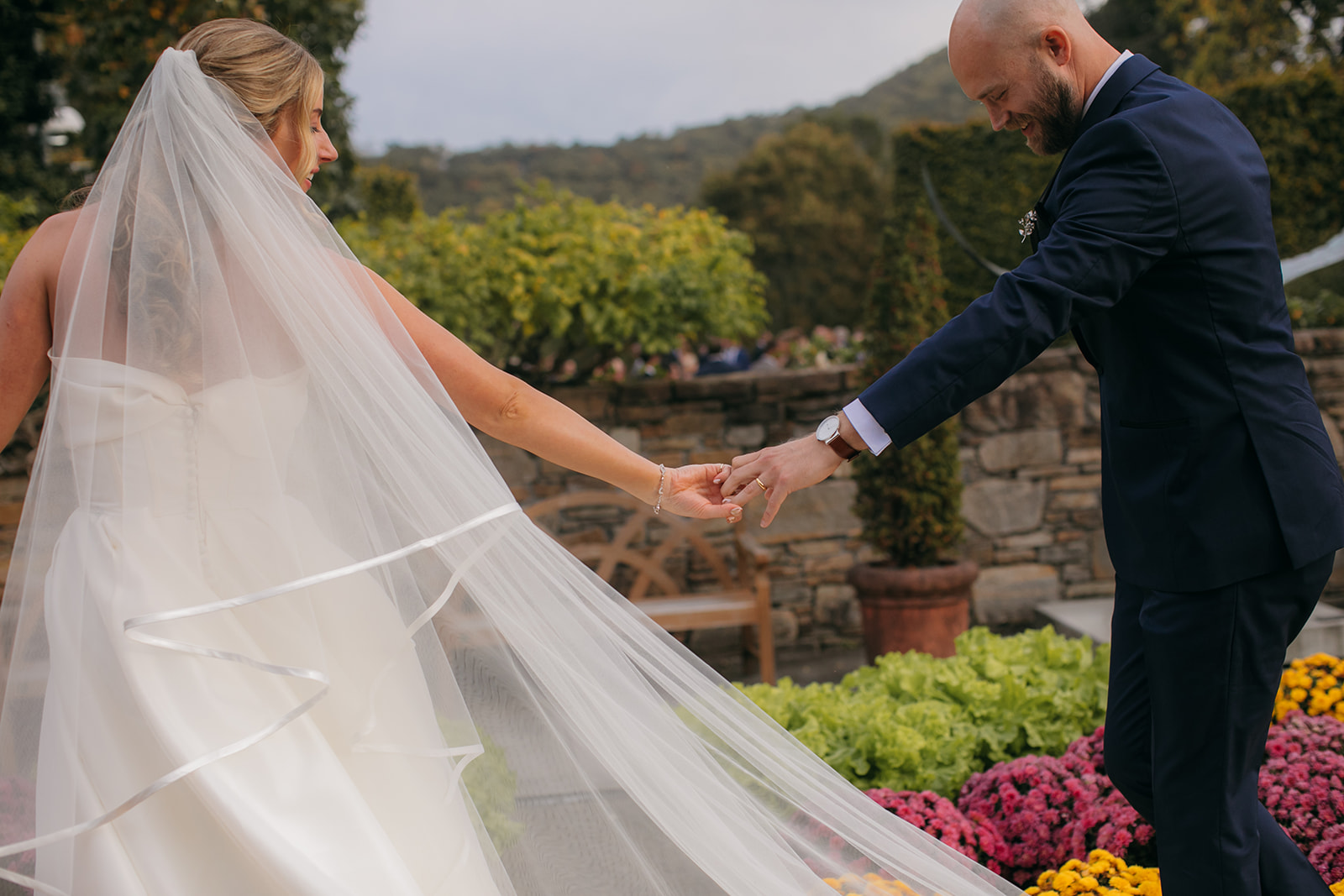 Bride and groom walking hand in hand through colorful gardens at a North Carolina State Arboretum wedding.