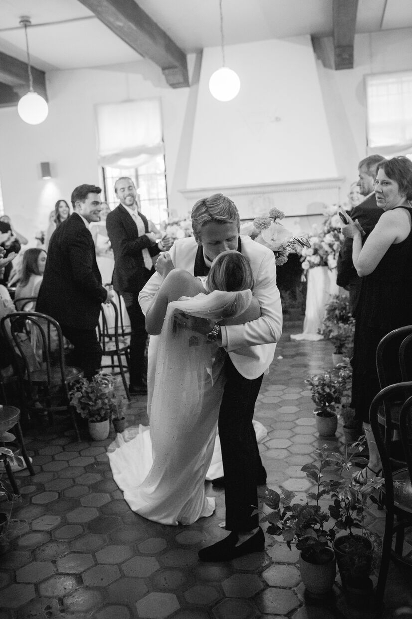 groom and bride kissing at end of aisle after vow exchange at common house chattanooga