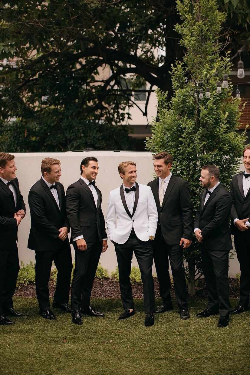 groomsmen and groom smiling outside in the garden space at common house chattanooga 
