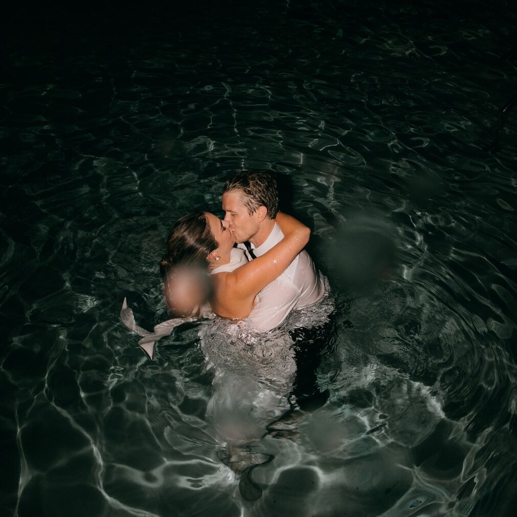 groom and bride sharing a kiss in pool after jumping in after reception at common house chattanooga