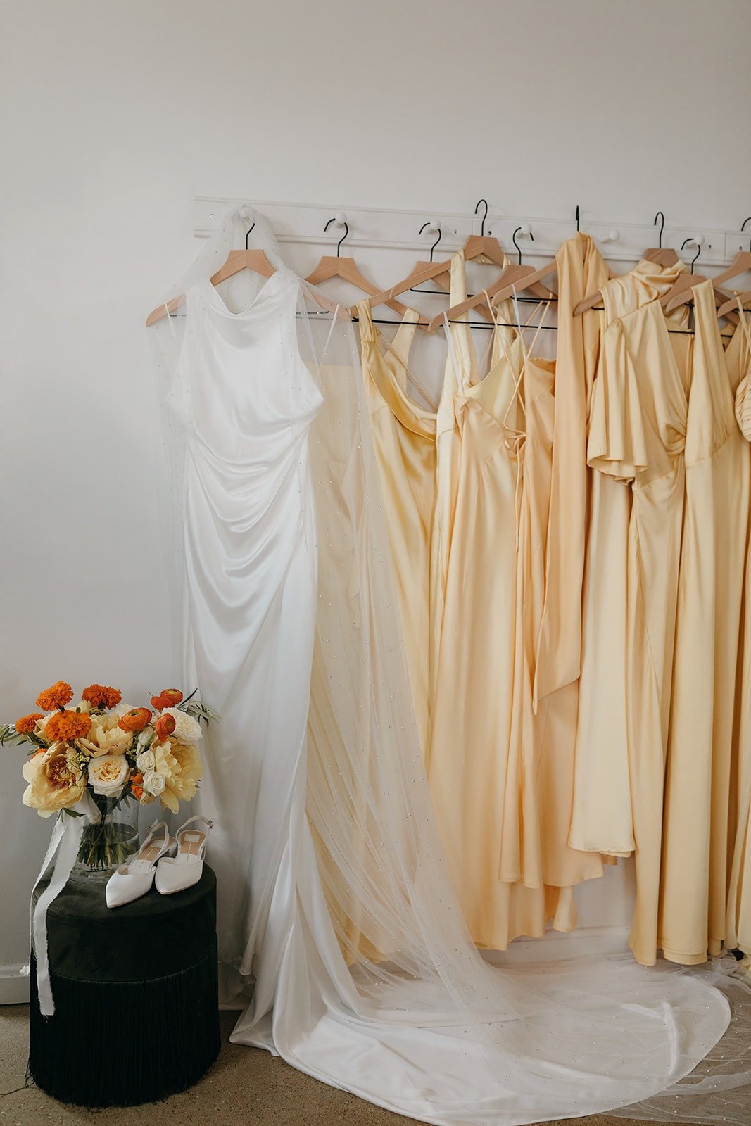 bride's dress and bridesmaid's dresses hanging up by flowers at common house chattanooga for wedding