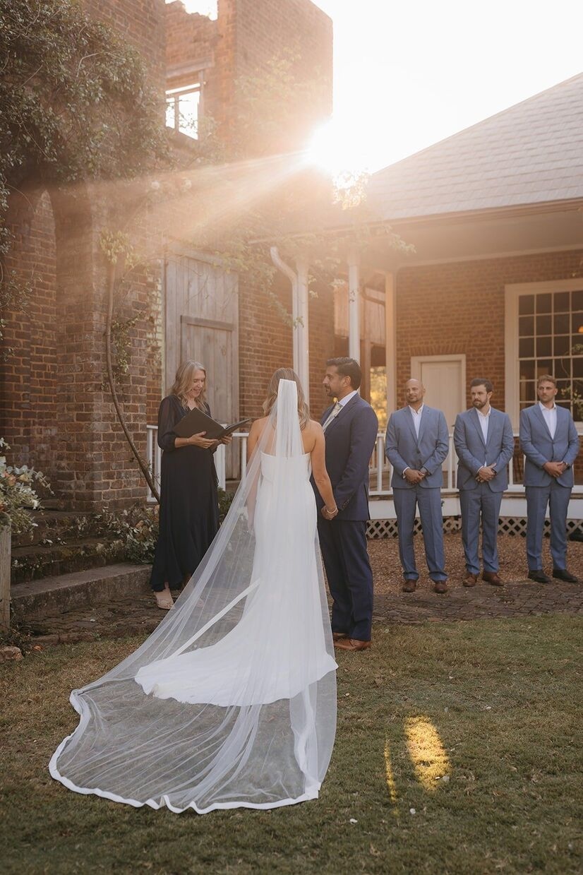 Bride and groom and officiant during a ceremony with sunlight streaming in at Barnsley Garden wedding.