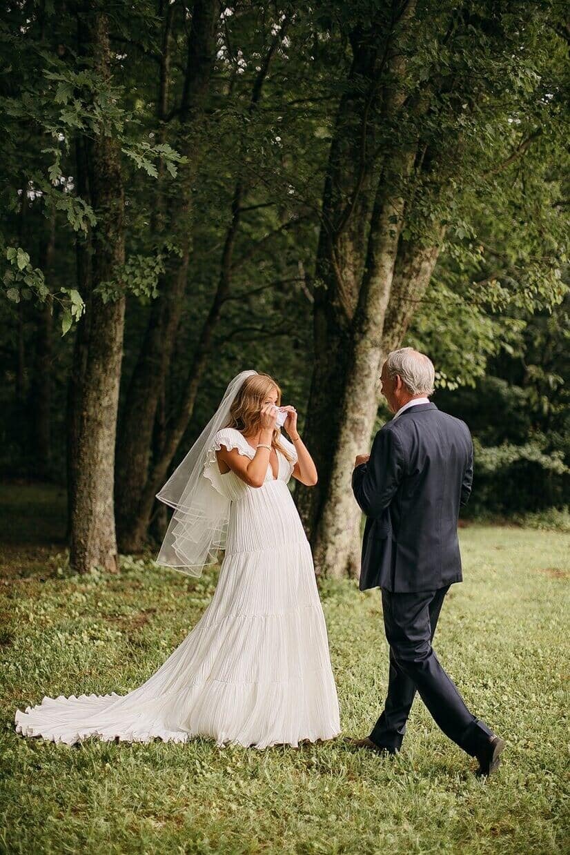 bride crying when she sees her dad in a field.